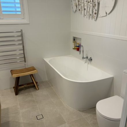 Elegant bathroom featuring a freestanding bathtub, white panel walls, and a heated towel rack